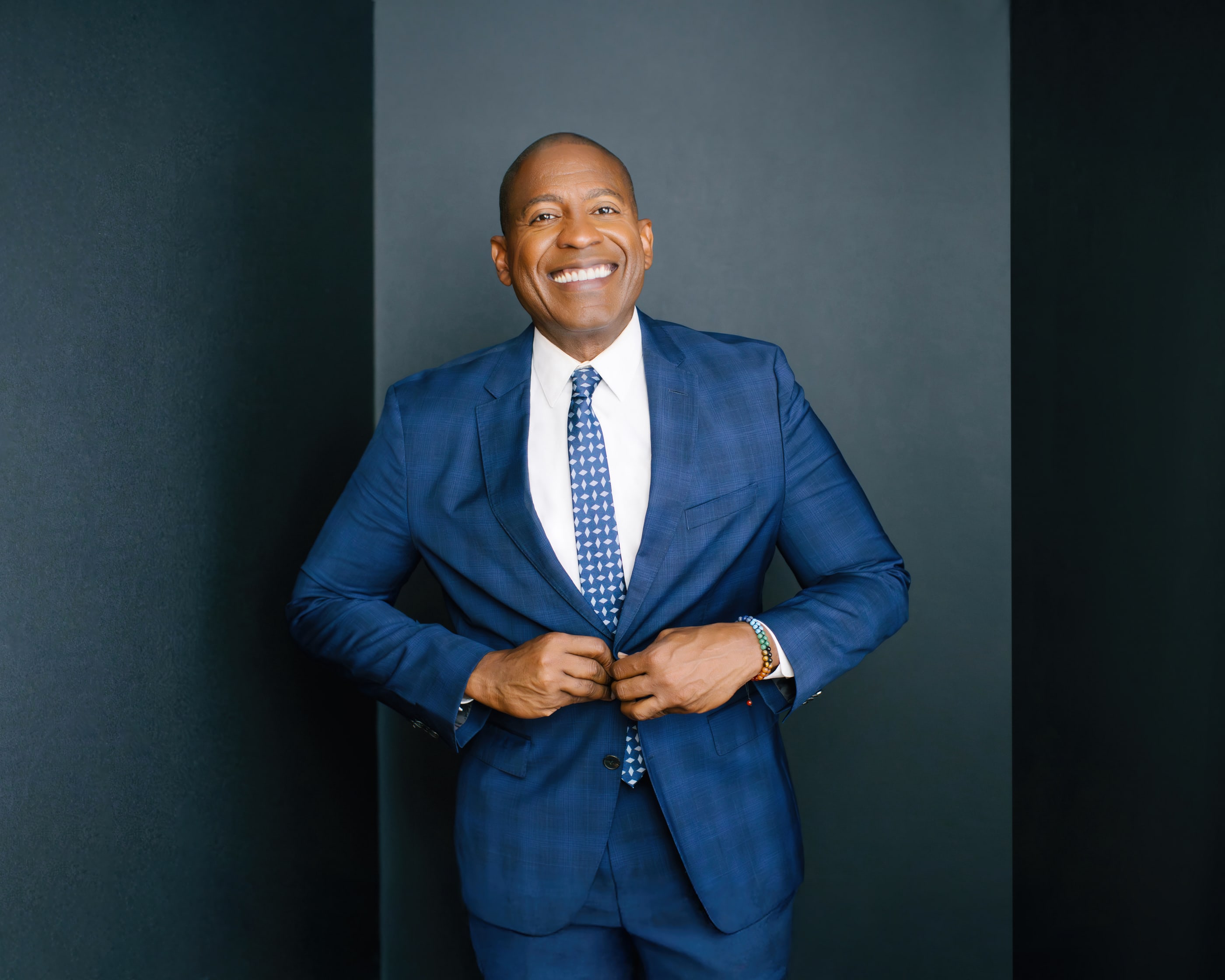 Carlos Watson today, smiling in a blue suit