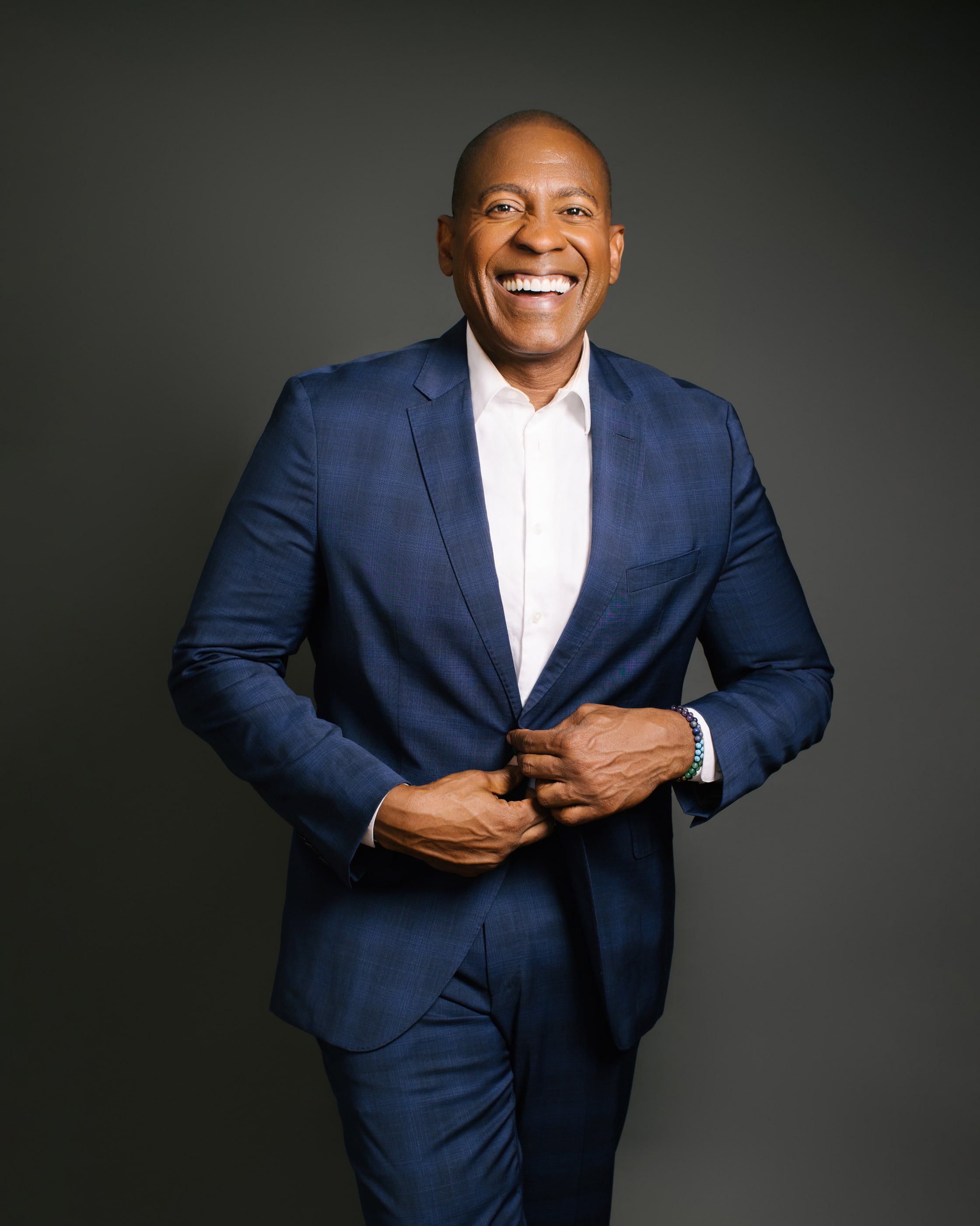 Carlos Watson smiling in a blue suit